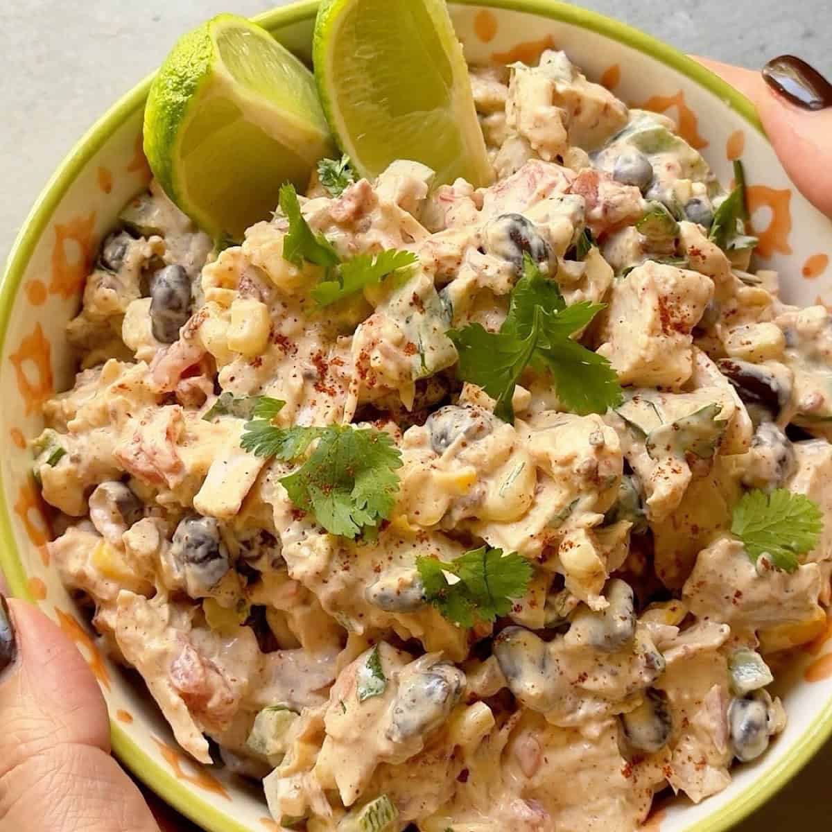 Southwest chicken salad in a bowl with cilantro and lime garnish.
