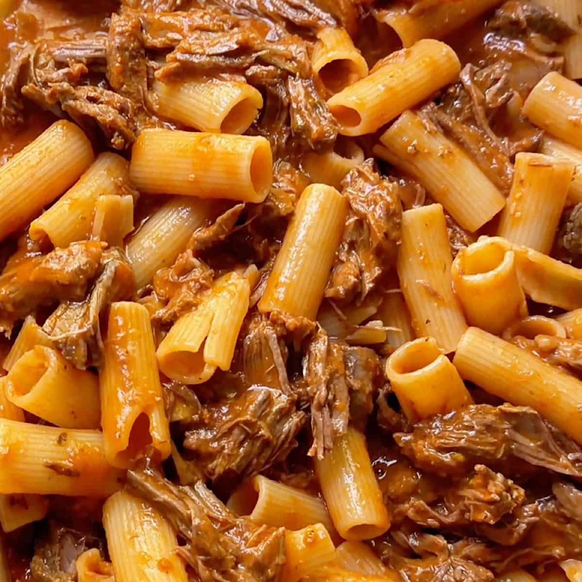 Tossed beef ragu rigatoni in a casserole dish.