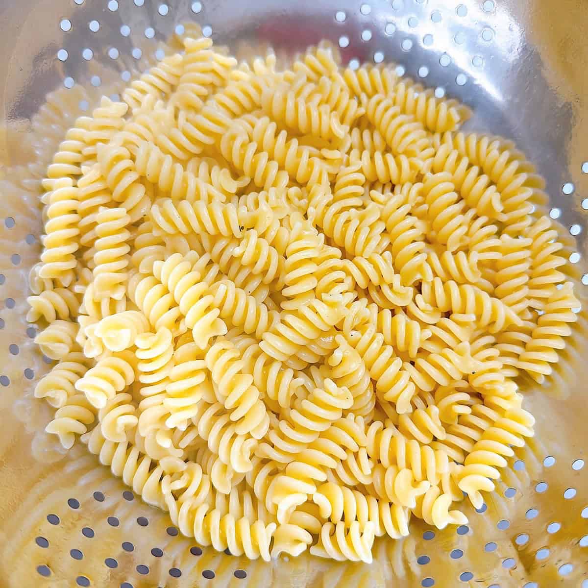 Boiled fusilli pasta draining in a colander.