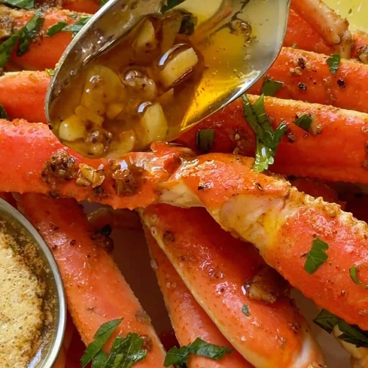 Spooning garlic butter over oven baked crab legs.