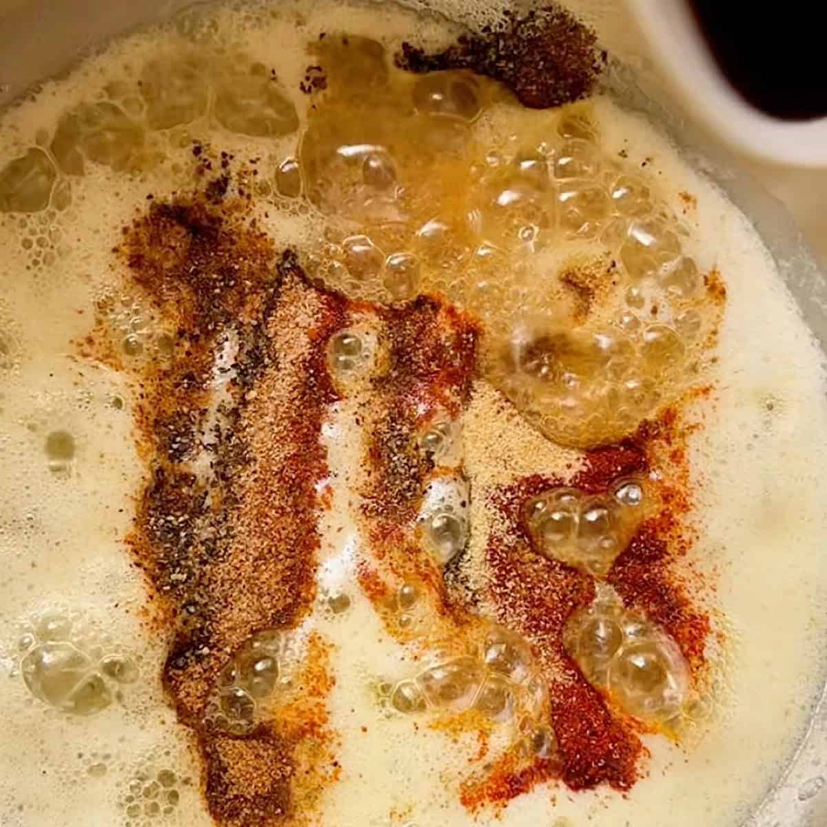 Garlic butter with cajun seasoning heating on a stove top.
