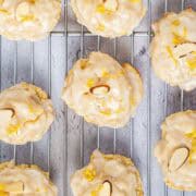 Italian lemon ricotta cookies on a wire rack with lemon glaze, sliced almond, and lemon zest.