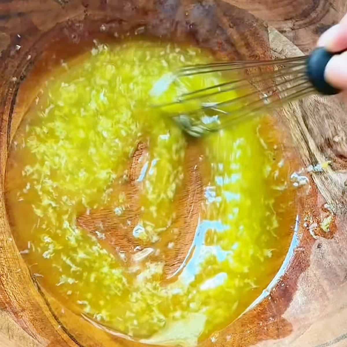 Whisking the lemon parmesan dressing in a bowl.