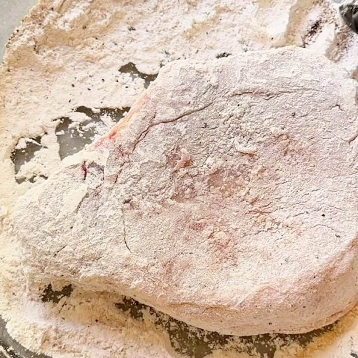 A seasoned pork chop dredged in flour.