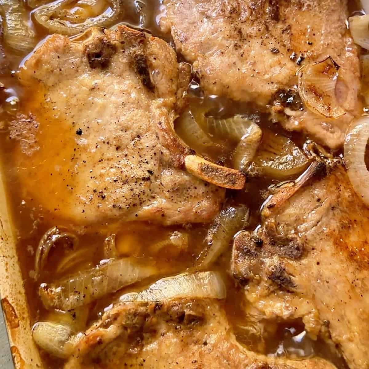 The smothered pork chops removed from the even resting in a bubbly gravy.