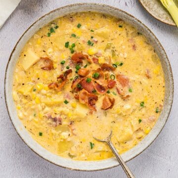 Hearty corn and potato chowder with bacon and chives in a bowl.