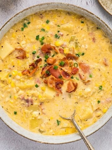 Hearty corn and potato chowder with bacon and chives in a bowl.