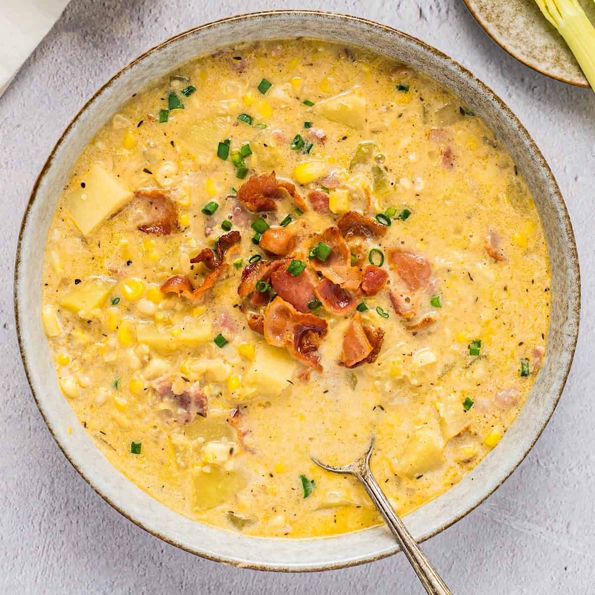 Hearty corn and potato chowder with bacon and chives in a bowl.