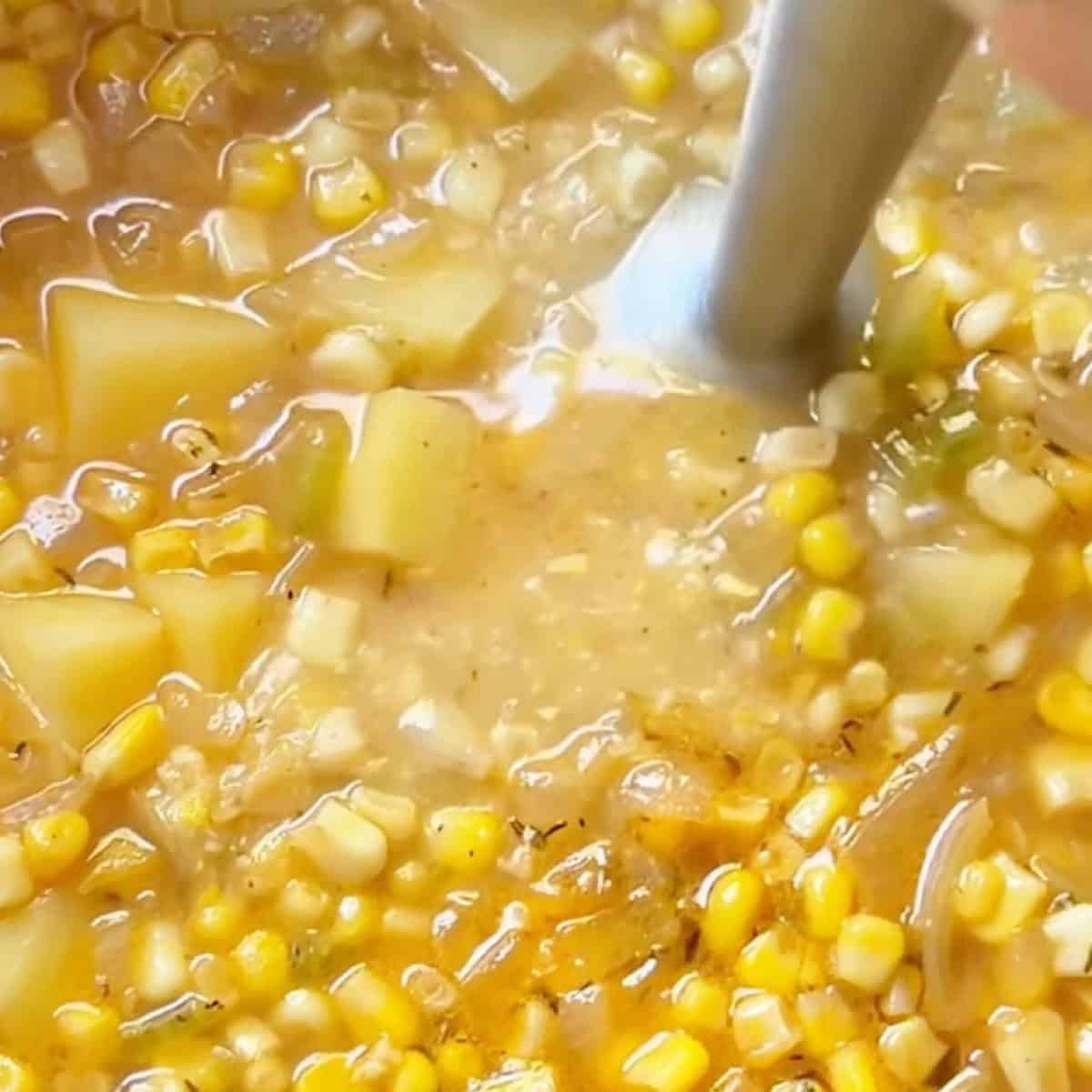 An immersion blender thickening the soup.