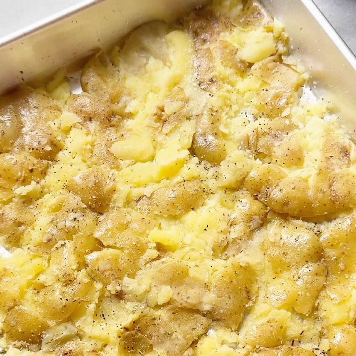 Yellow potatoes smashed on sheet pan.