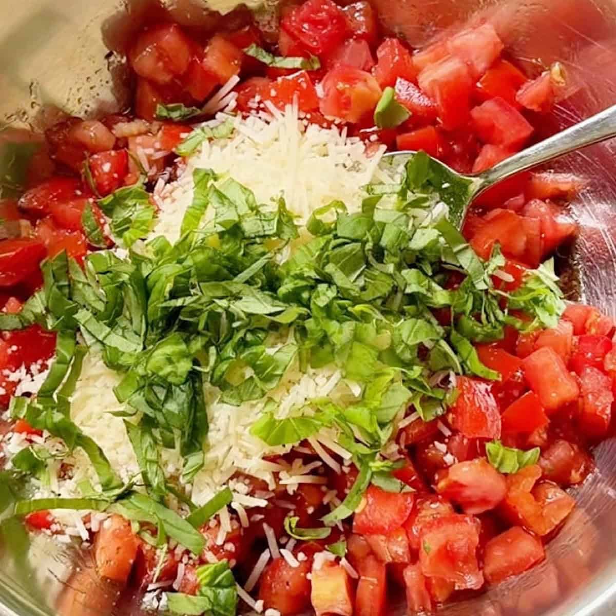 Mixing bruschetta topping in a bowl.
