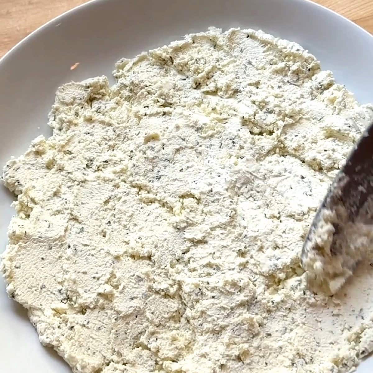 Layering the spreading Boursin cheese into a shallow white bowl.