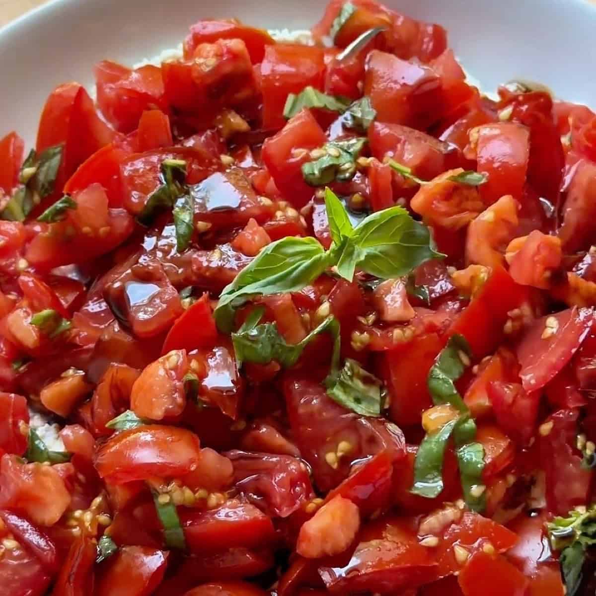 Prepared bruschetta dip with basil leaf on top for garnish.