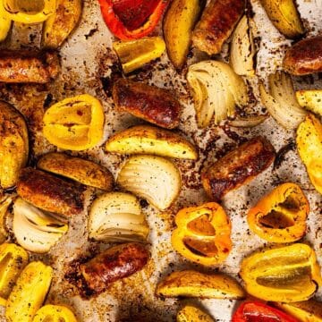 A full sheet pan showing the seasoned crispy browned edges of the sausage, potatoes, and peppers.