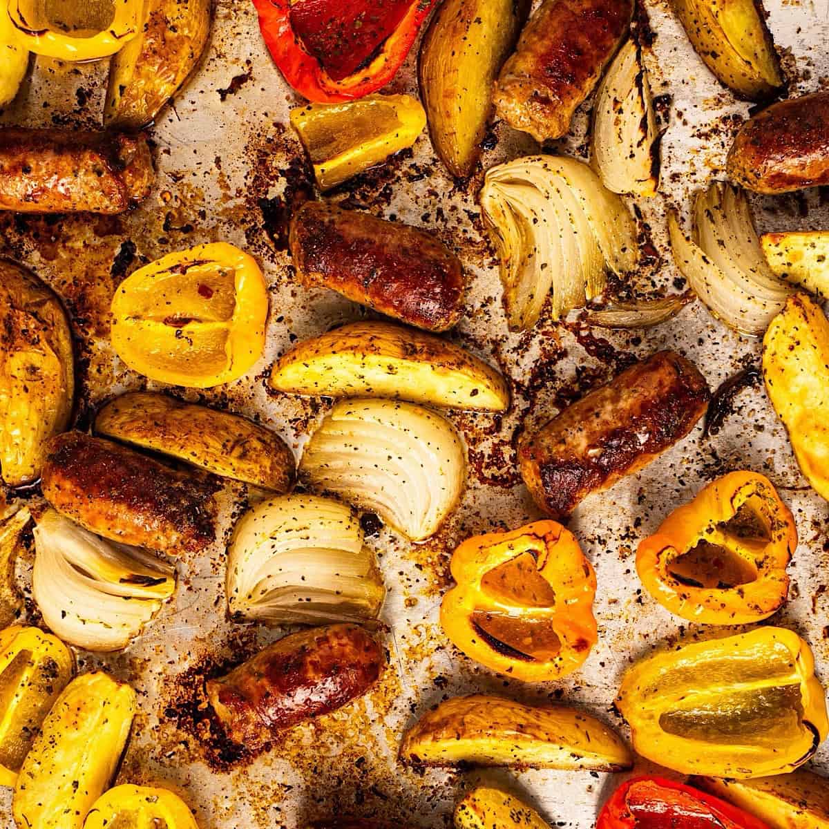 A full sheet pan showing the seasoned crispy browned edges of the sausage, potatoes, and peppers.