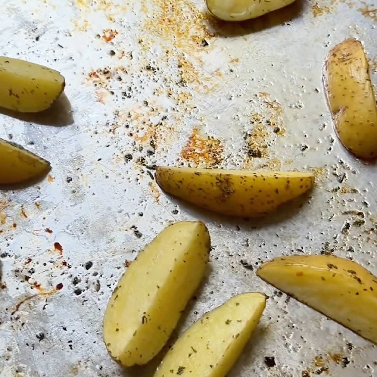 Potatoes on the sheet pan after first bake with browned edges.