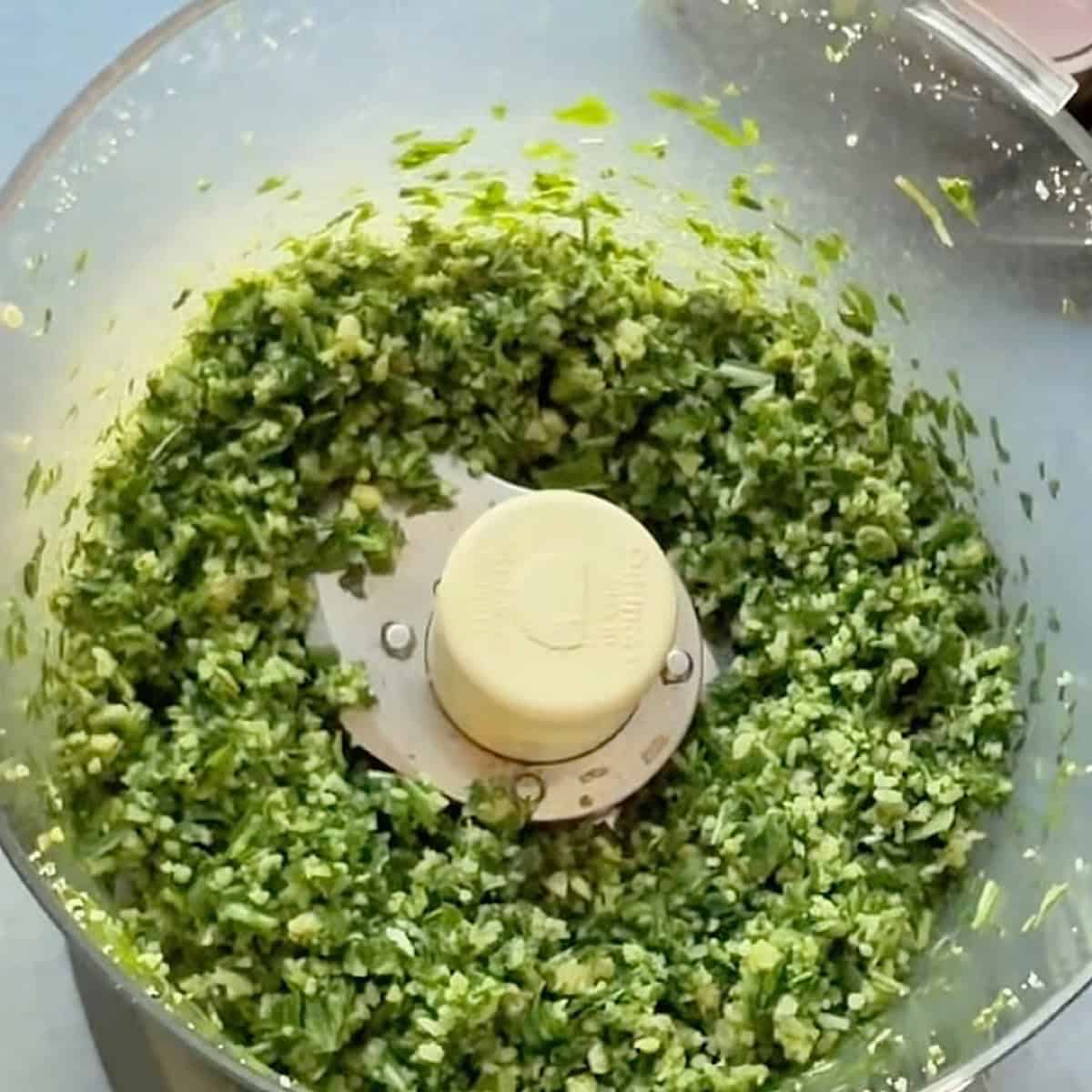 Basil arugula pesto ingredients finely chopped in the food processor.