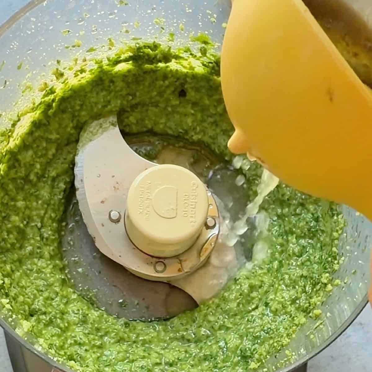 Adding fresh lemon juice to the pesto blended with olive oil.