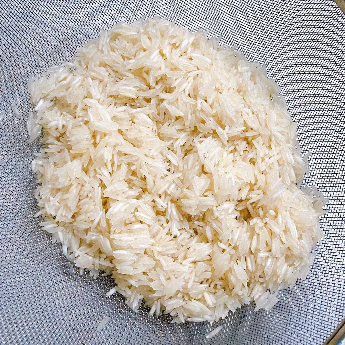Rinsed basmati rice in a mesh strainer.