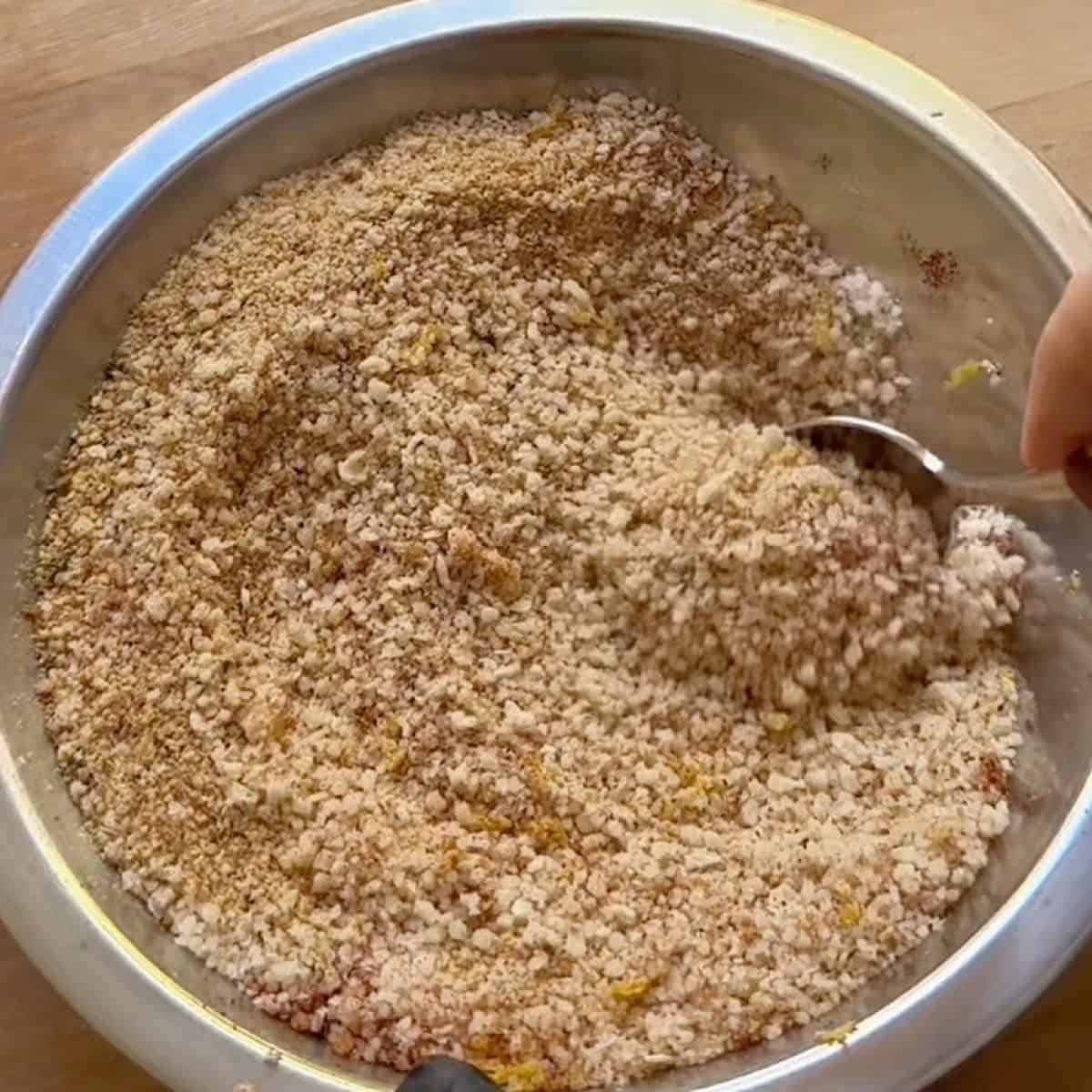 Stirring the breadcrumb mixture with a spoon.