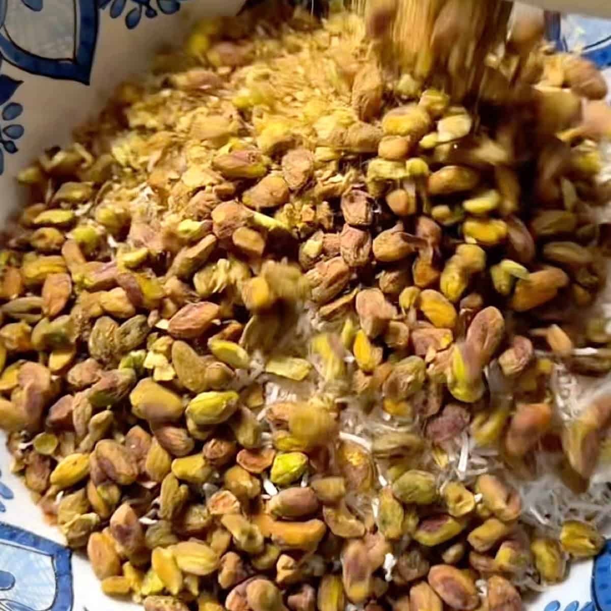 Combining the rolled oats, shredded coconut, and pistachios in a large mixing bowl.