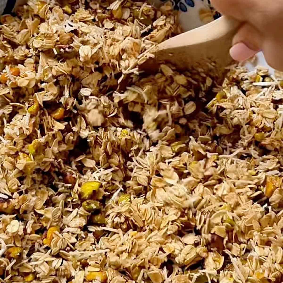 Combining the heated honey and oil with the granola and pistachios.