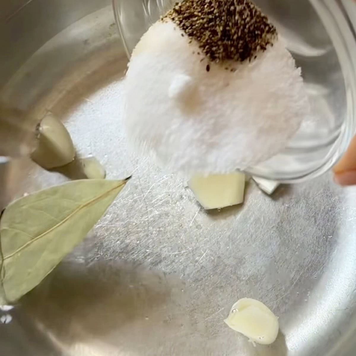 Adding salt, sugar, and pepper to vinegar and water brine.