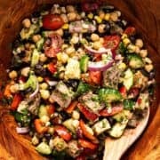 Steak chimichurri dense bean salad tossed in a wooden bowl with wooden spoon.