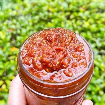 Holding sundried tomato pesto in a jar outside.