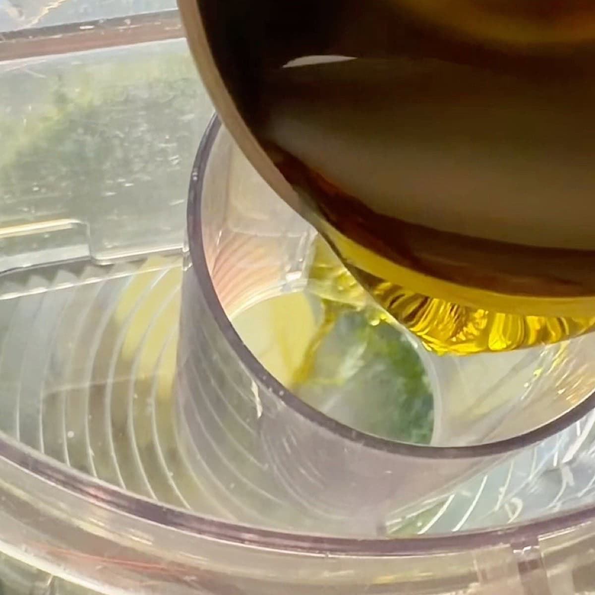 Adding olive oil through the top hole of the food processor.