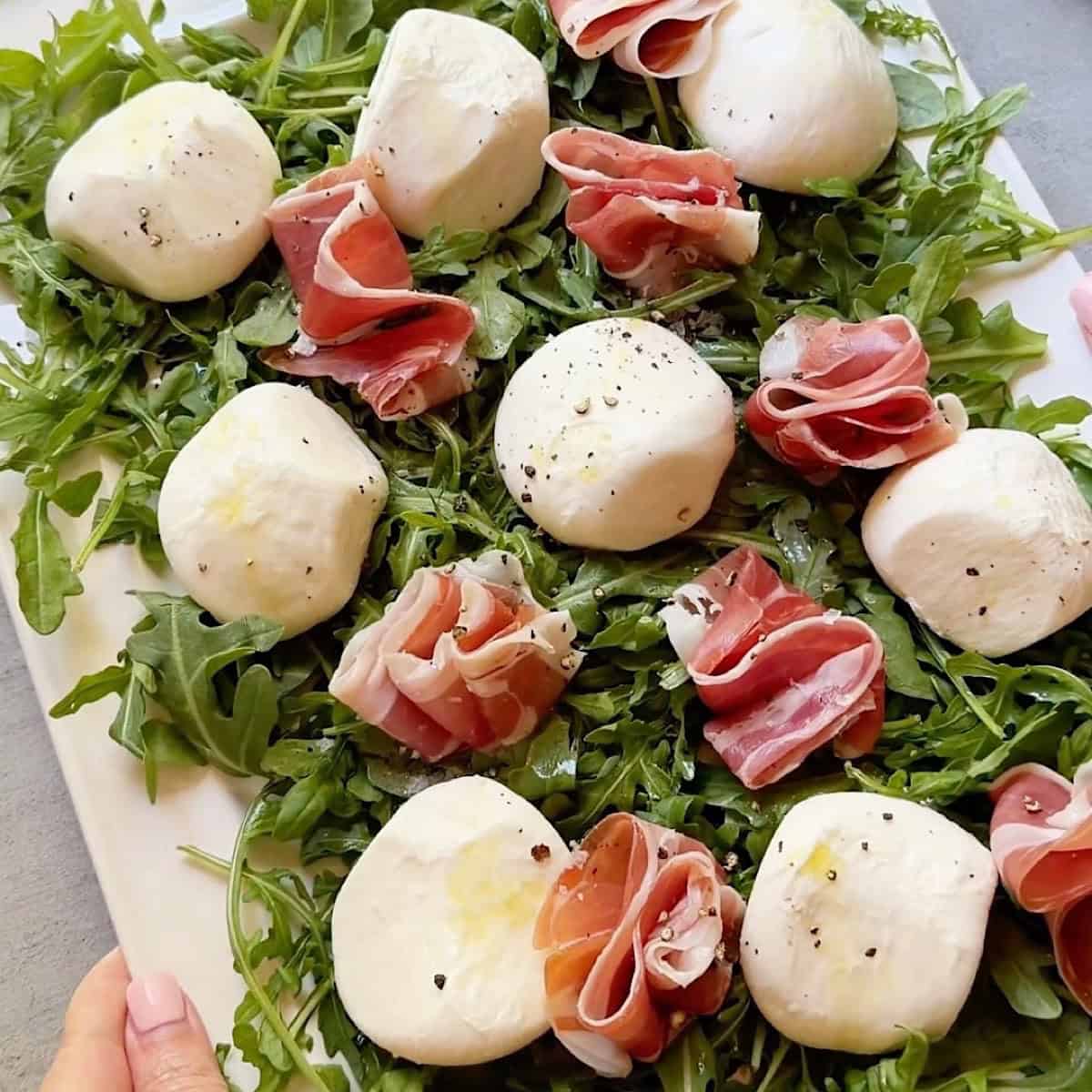 Holding a platter of burrata prosciutto for entertaining.