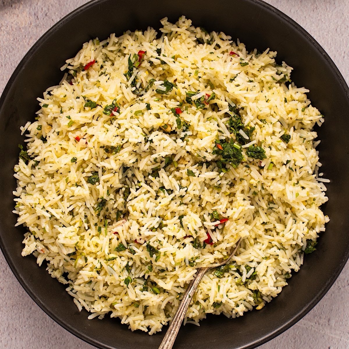 Chimichurri rice in a black bowl with parsley showing on top.