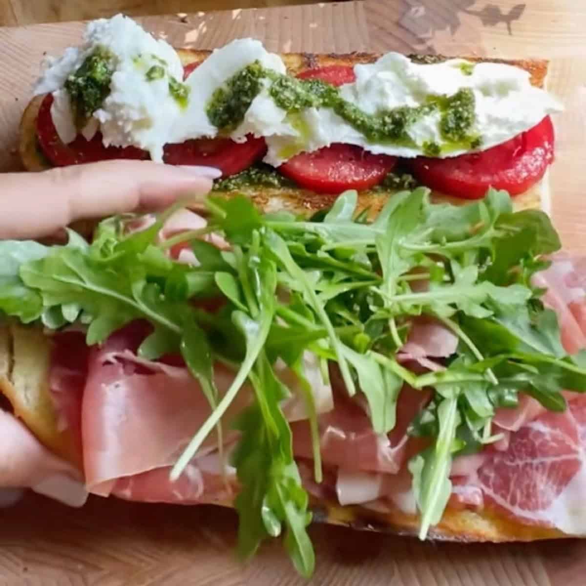 Basil pesto, tomato, arugula, italian meats and cheese on the open faced french loaf.