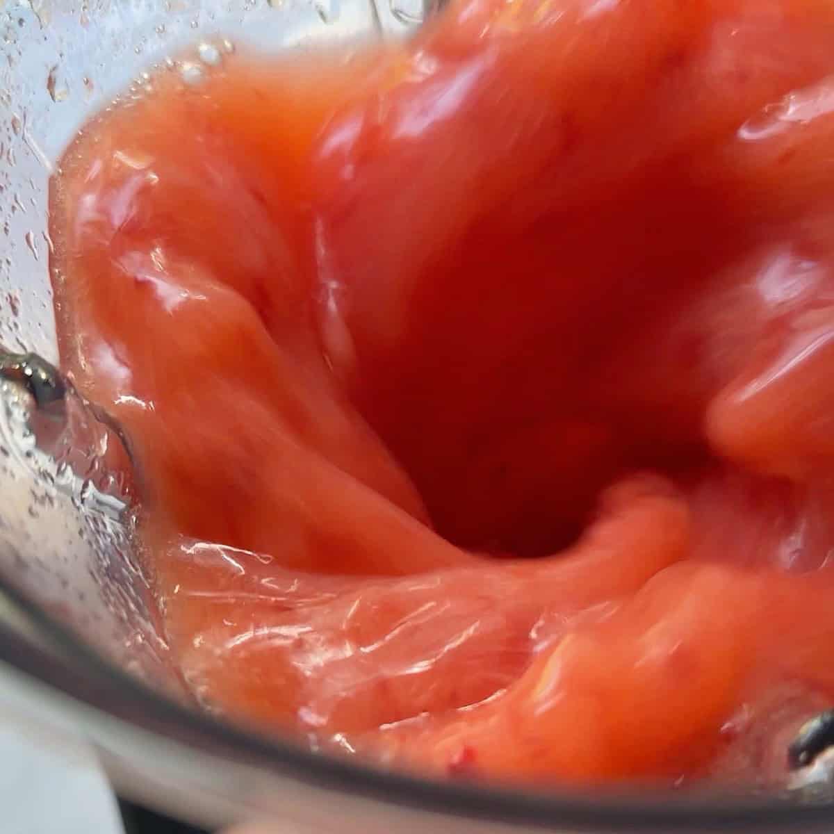 Strawberries and fresh lemon juice swirling in a blender.