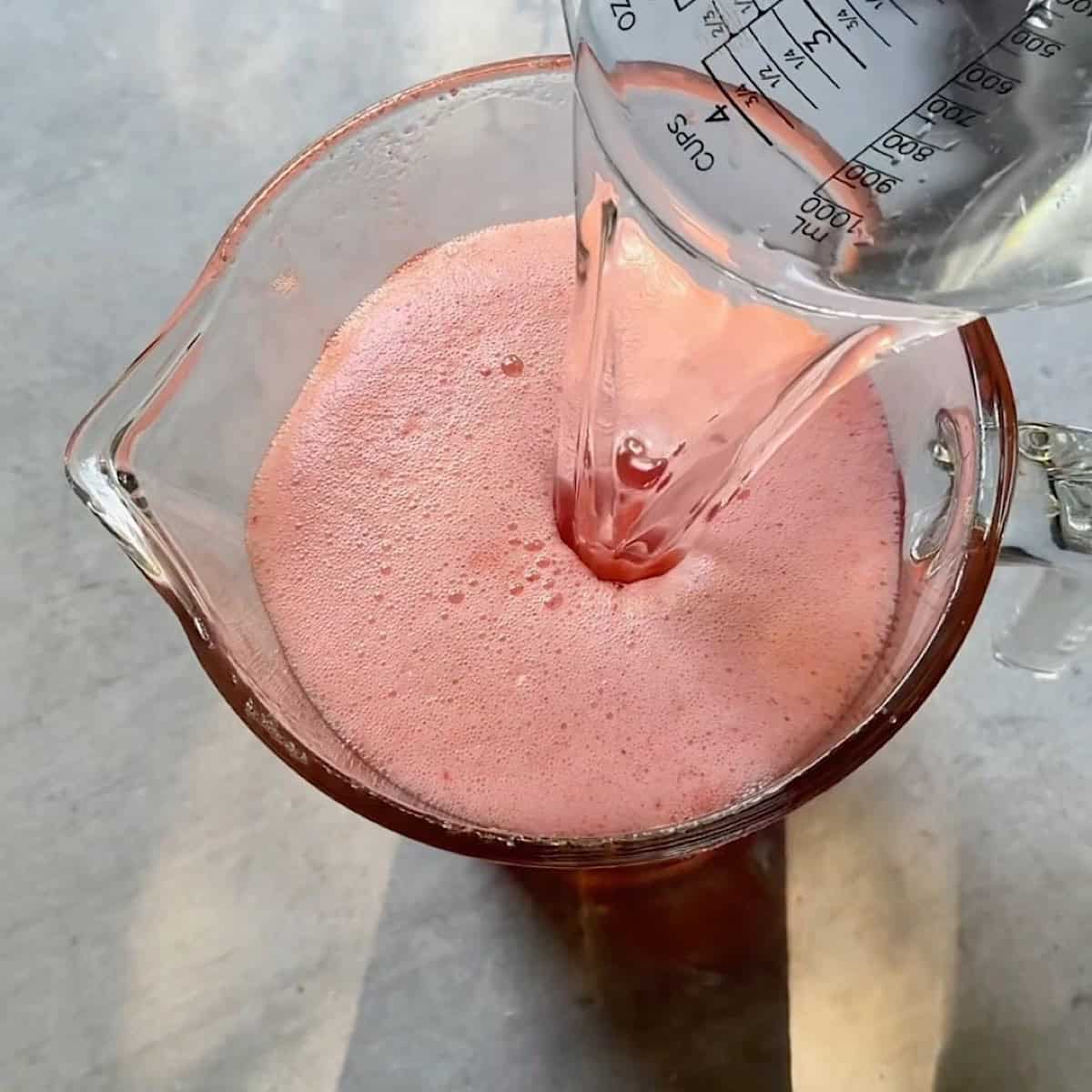 Adding water to the strawberry lemonade.