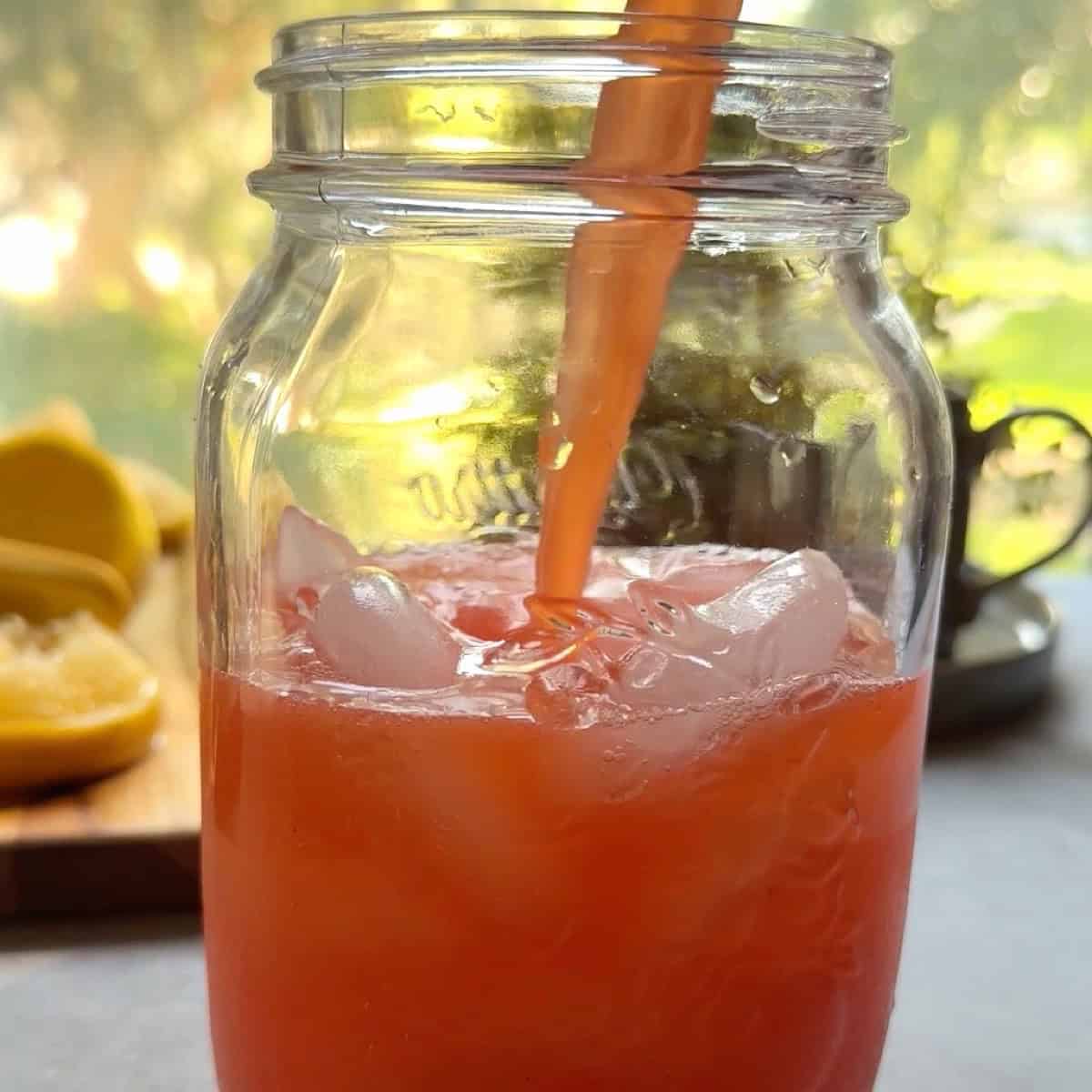 Pouring the fresh strawberry lemonade in a mason jar over ice.