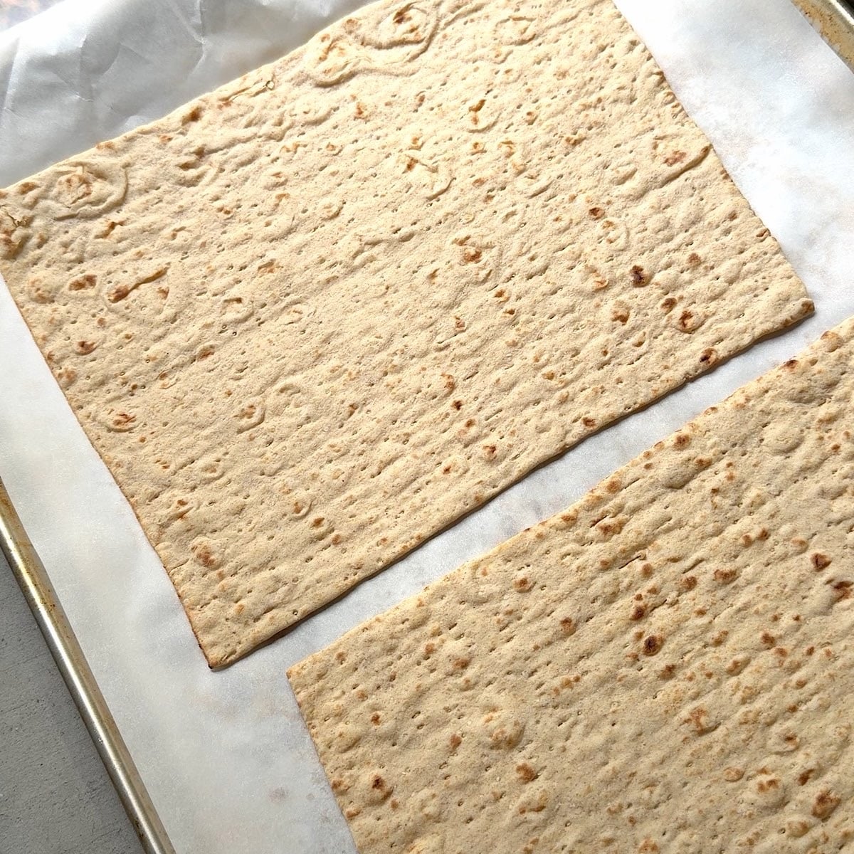 Parchment lined baking sheet with lavash bread on top.