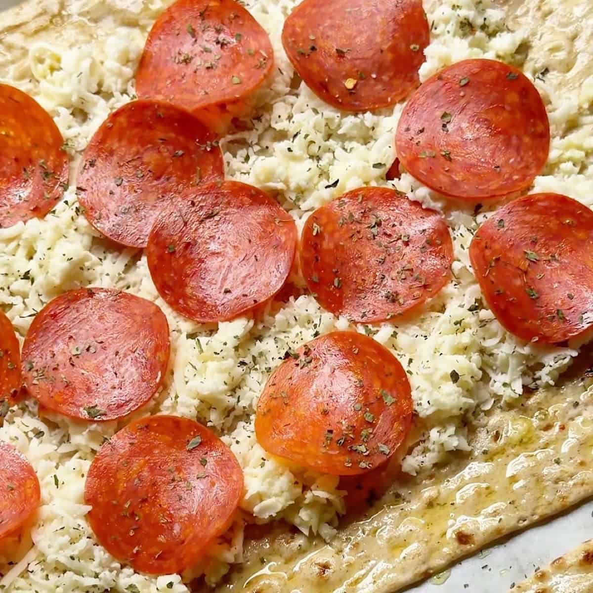 Mozzarella cheese, pepperoni, and Italian seasoning on top of lavash bread.