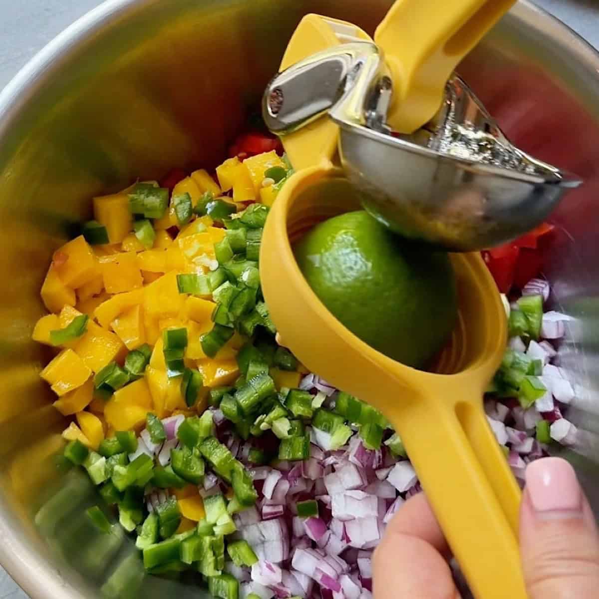 Squeezing lime over mango, tomato, red onion, and jalapeno.