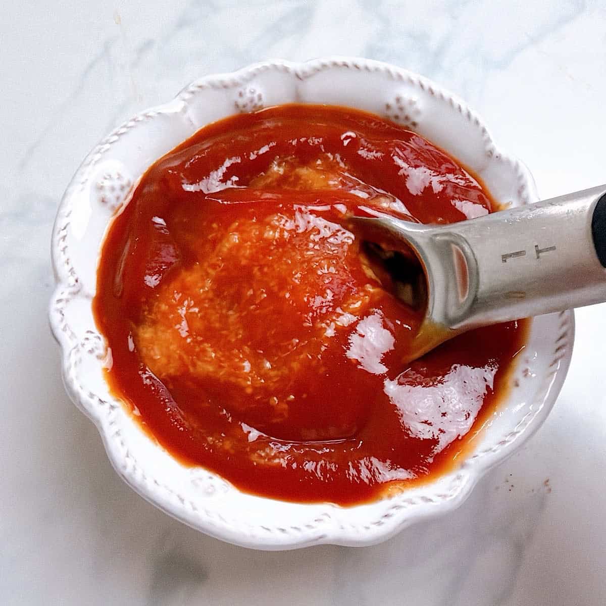Mixing horseradish sauce with ketchup in a small decorative bowl.