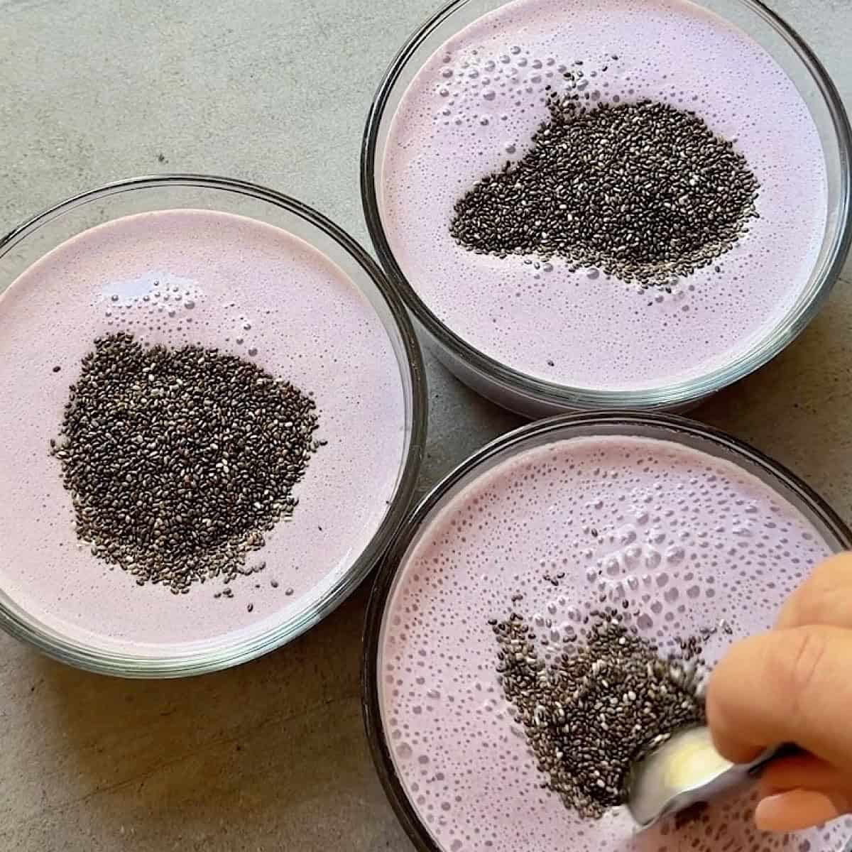 Stirring chia seeds into each chia pudding container.