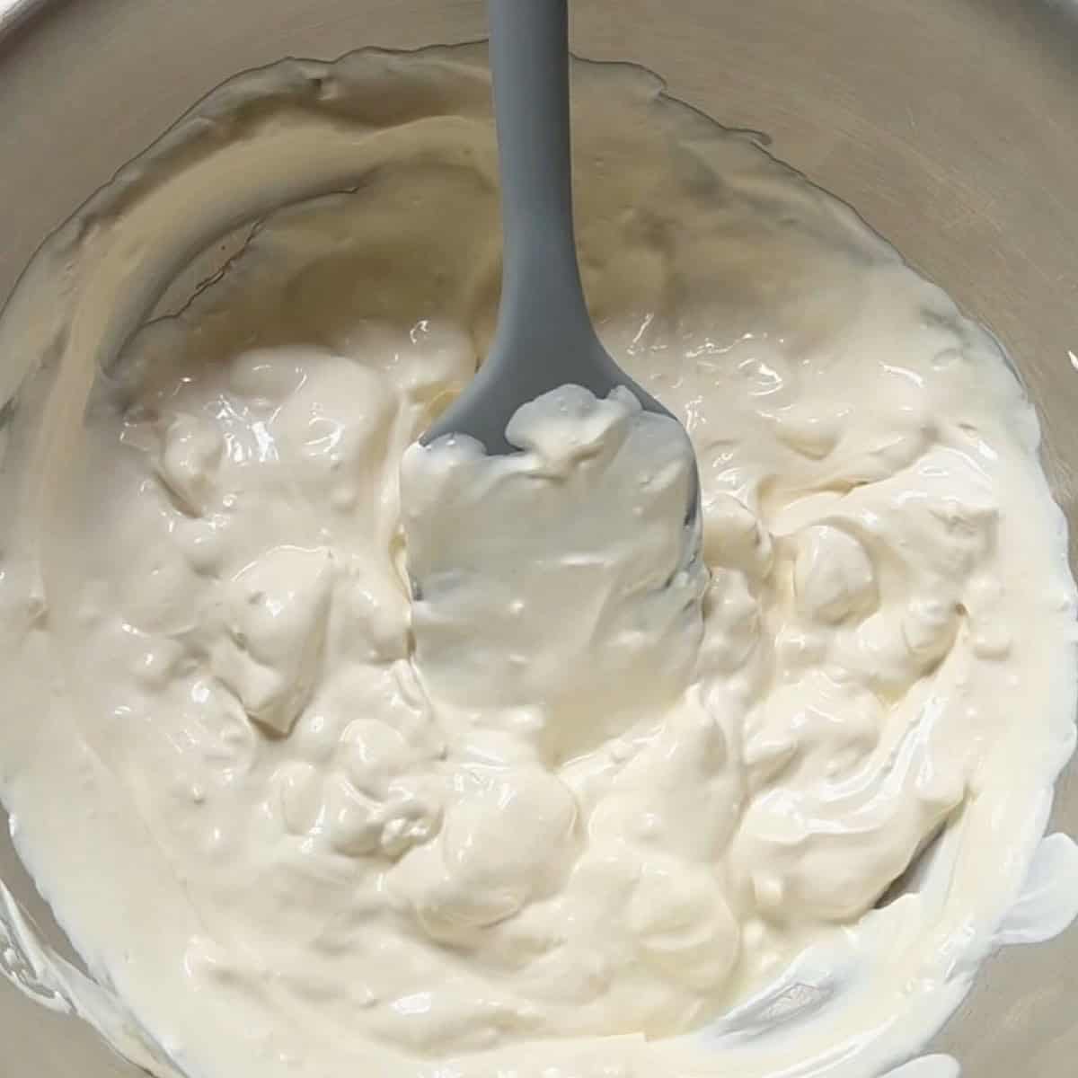 Mixing the creamy base of sour cream, mayonnaise, and cream cheese.