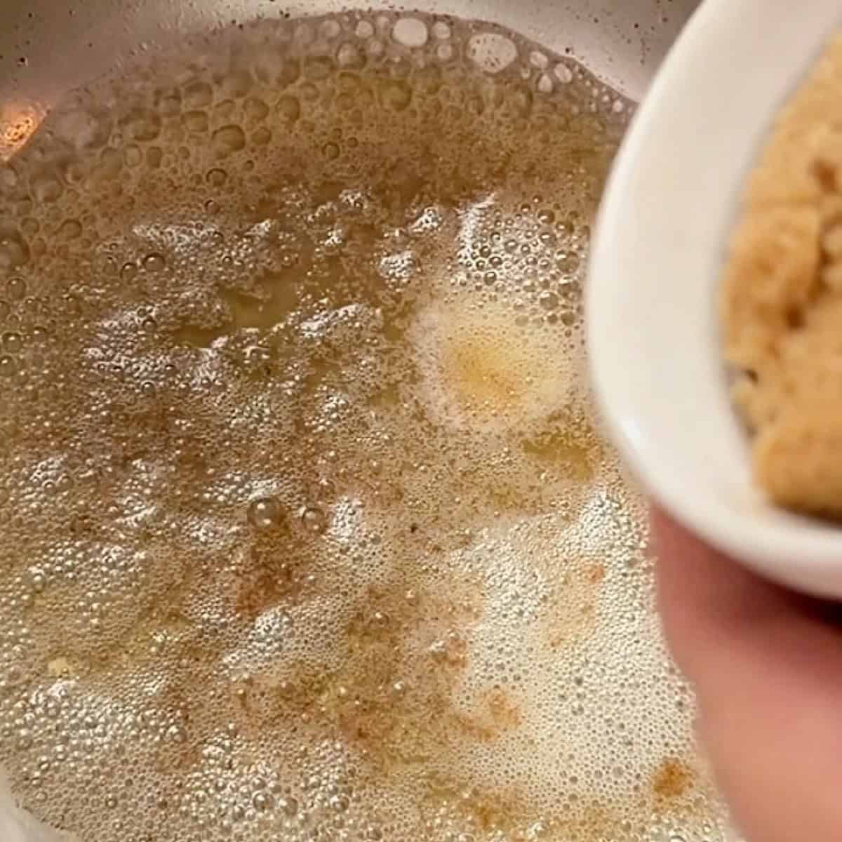 Heated browned butter foaming in a pan.