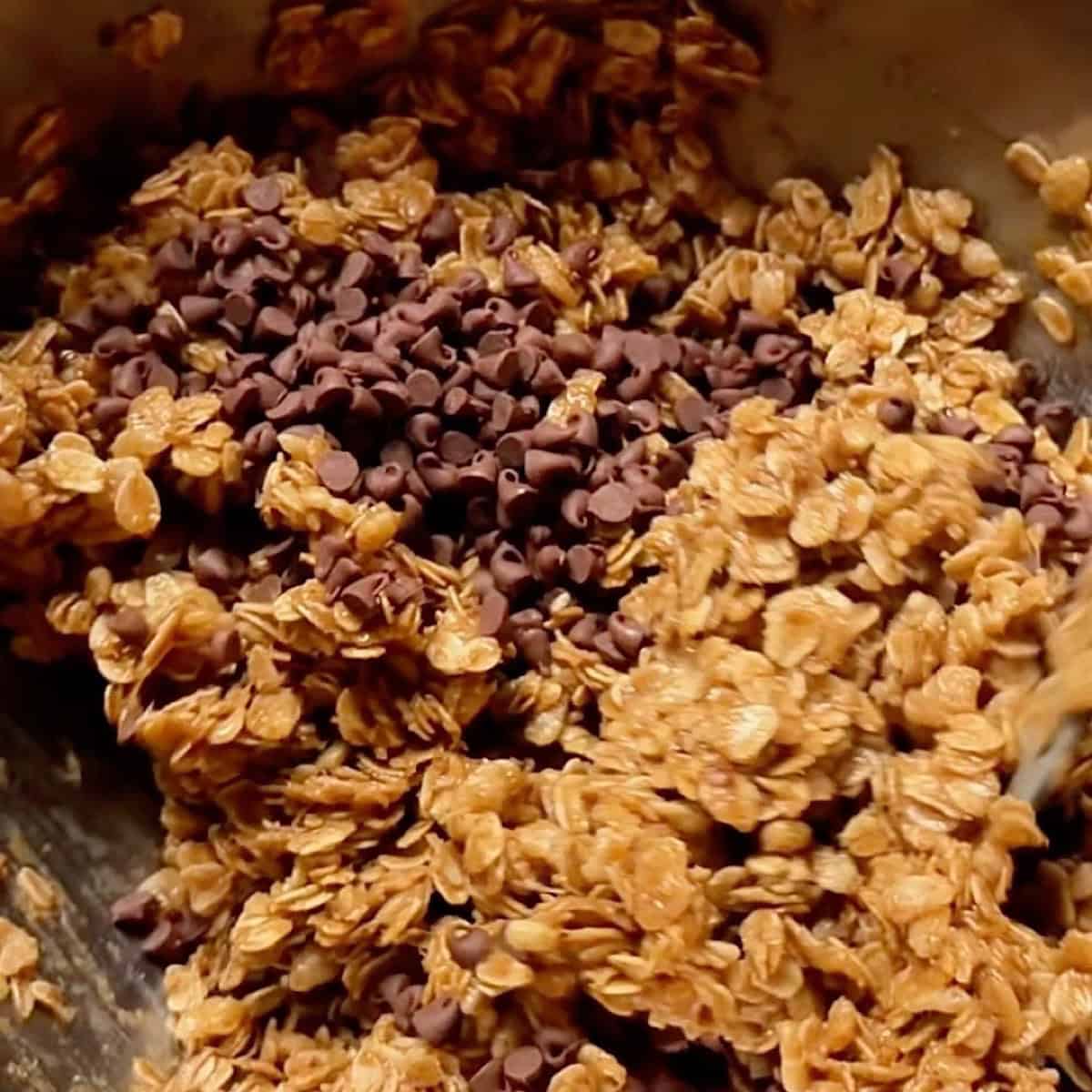 Folding mini chocolate chips into the granola mix.
