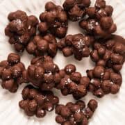 A fluted decorative plate with frozen chocolate covered blueberries clustered together and topped with flaky salt.