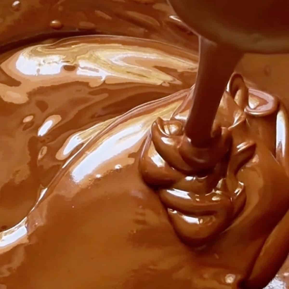 Showing the smooth melted chocolate drizzling from a spoon.