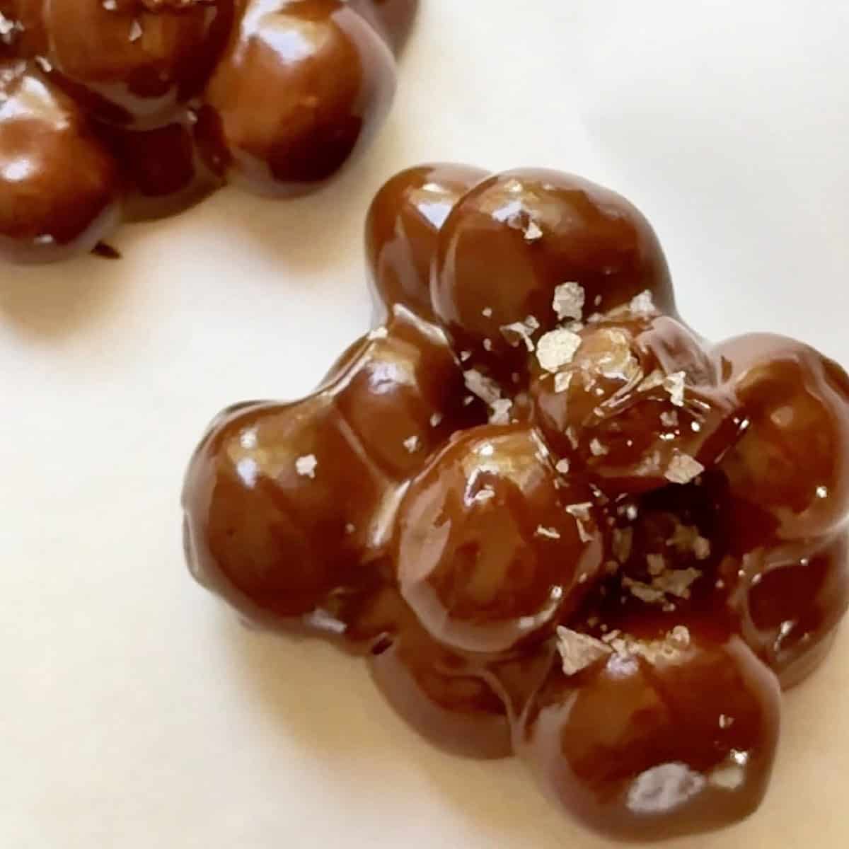 Two blueberry clusters formed on parchment paper with flaky salt on top.