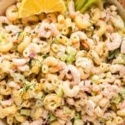 Creamy shrimp macaroni salad with a lemon wedge and celery stick.
