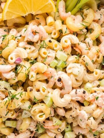 Creamy shrimp macaroni salad with a lemon wedge and celery stick.