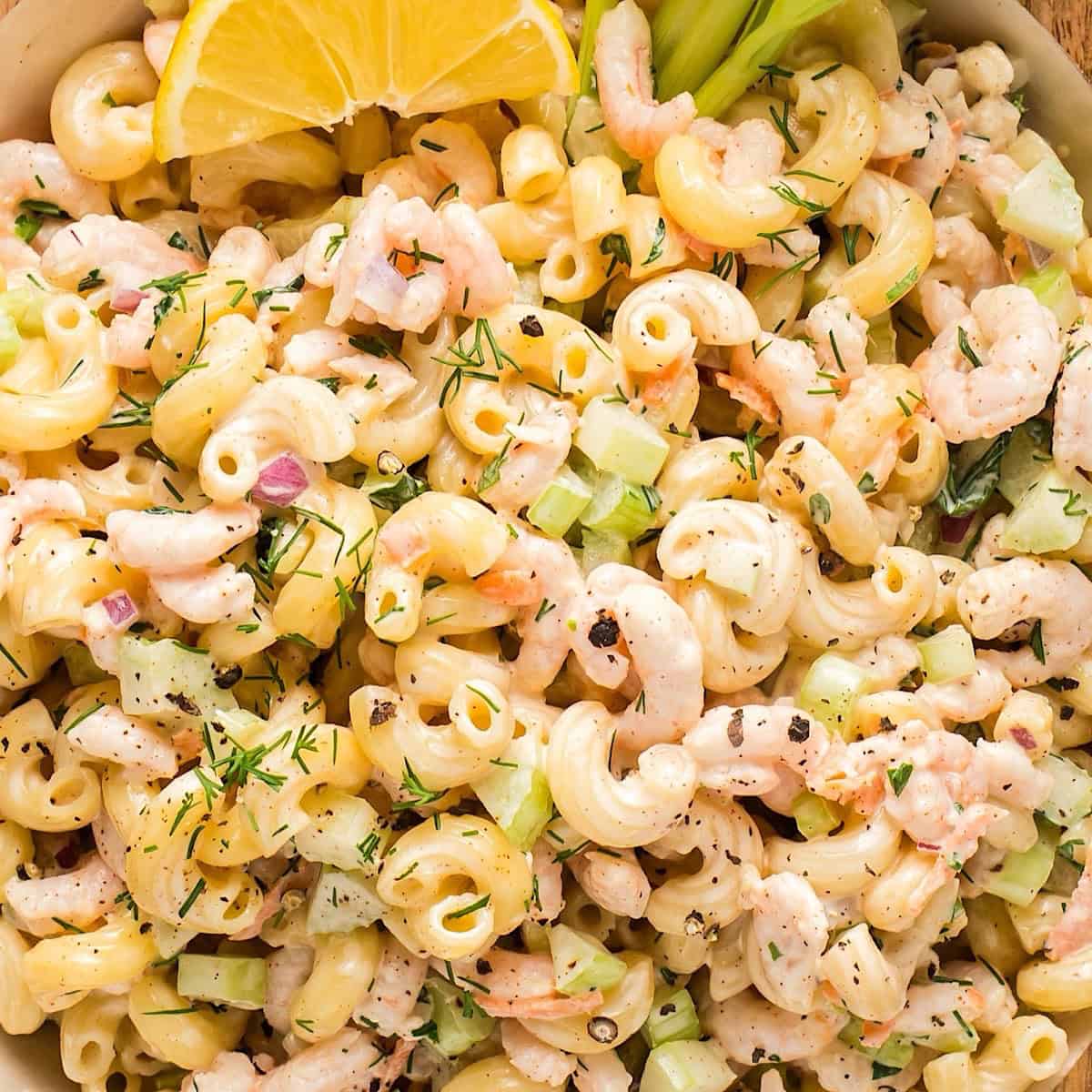 Creamy shrimp macaroni salad with a lemon wedge and celery stick.